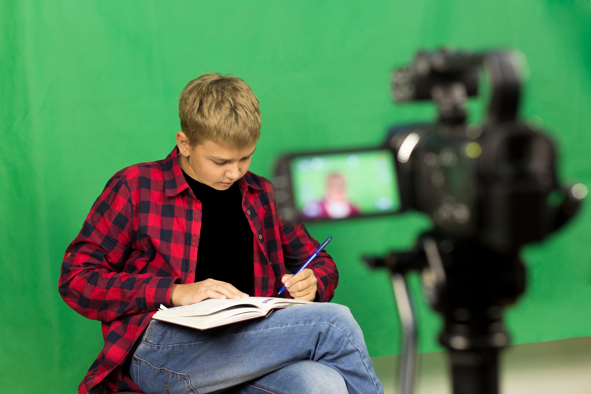 Young boy blogger records video on a green background