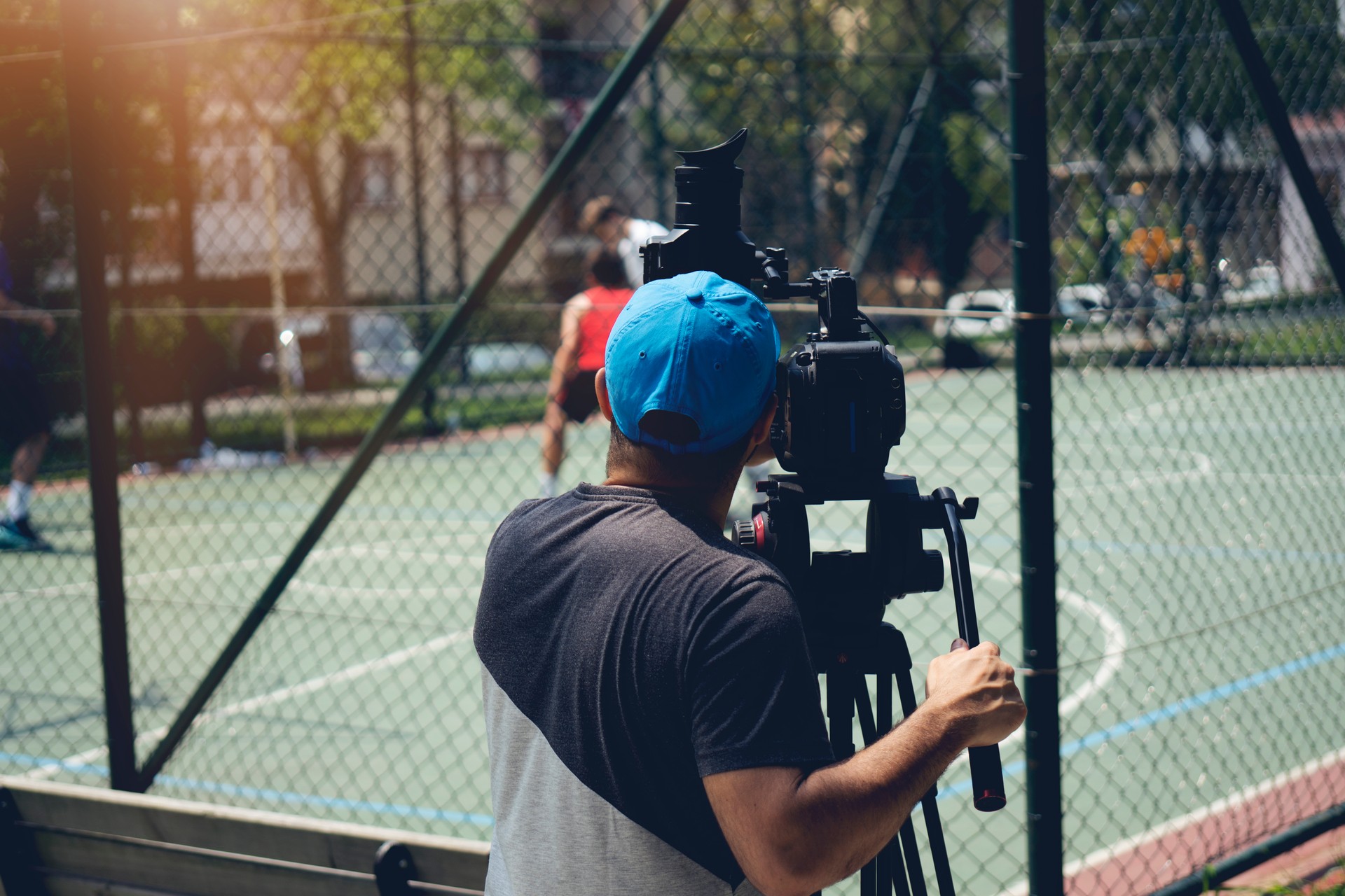 Blurry image of movie shooting or video production and film crew team with camera equipment at outdoor location and light flare effect.